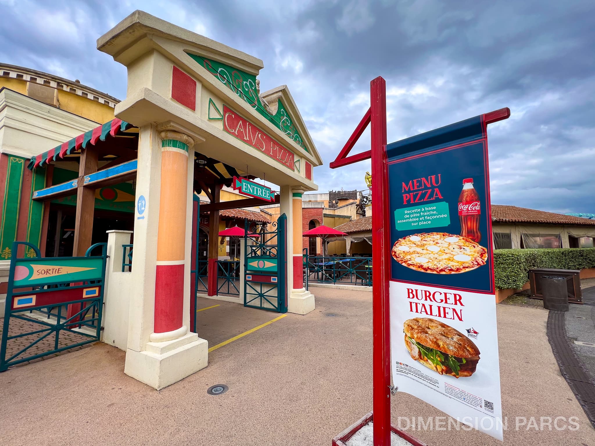 Entrée du restaurant Caïus Pizza avec une pancarte montrant le menu pizza et le burger italien